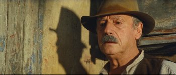 Movie still from “Manon of the Spring” (1986), directed by Claude Berri – An older man wearing a cowboy hat in front of a brick wall; Close Up shot, Low angle