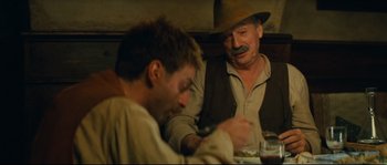 Movie still from “Manon of the Spring” (1986), directed by Claude Berri – Two men sitting at a dinner table , one of which has a mustache; Medium shot, Over the shoulder angle