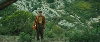 Movie still from “Manon of the Spring” (1986), directed by Claude Berri – A man standing on top of a hill holding a bag; Wide shot, Low angle