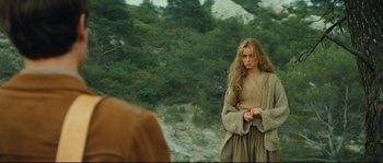 Movie still from “Manon of the Spring” (1986), directed by Claude Berri – A woman standing on top of a hill near a forest; Medium shot, Over the shoulder angle