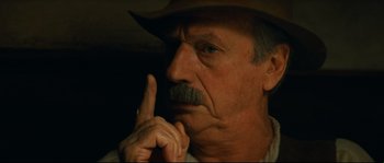Movie still from “Manon of the Spring” (1986), directed by Claude Berri – An older man wearing a hat and holding his index finger to his mouth; Close Up shot, Low angle
