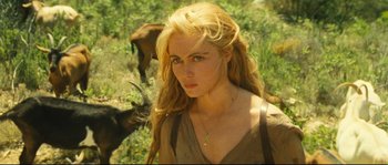 A woman with blonde hair and blue eyes standing in a field