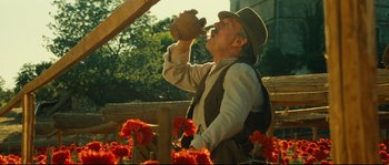 Movie still from “Manon of the Spring” (1986), directed by Claude Berri – An old man drinking from a cup in a field of flowers; Medium shot, Low angle