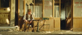 Movie still from “Manon of the Spring” (1986), directed by Claude Berri – An old man sitting on a chair in front of a table; Wide shot, Low angle