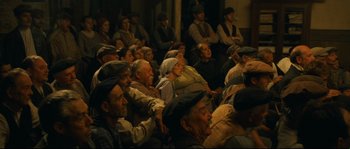 Movie still from “Manon of the Spring” (1986), directed by Claude Berri – A group of people sitting in a room watching something; Wide shot, High angle