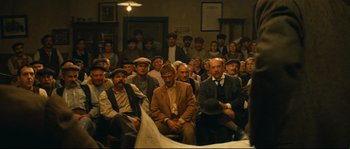 Movie still from “Manon of the Spring” (1986), directed by Claude Berri – A group of people sitting in a room; Wide shot, High angle