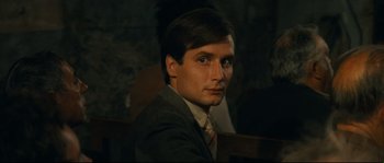 Movie still from “Manon of the Spring” (1986), directed by Claude Berri – A man in a suit sitting in front of a wall; Close Up shot, Over the shoulder angle