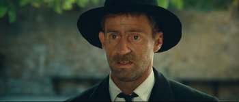 Movie still from “Manon of the Spring” (1986), directed by Claude Berri – A person wearing a suit and a hat; Close Up shot, Low angle