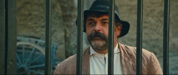 Movie still from “Manon of the Spring” (1986), directed by Claude Berri – A man with a beard wearing a black hat; Close Up shot, Low angle