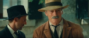 Movie still from “Manon of the Spring” (1986), directed by Claude Berri – A man in a hat and a tie talking to another man in a hat; Close Up shot, Over the shoulder angle