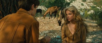 Movie still from “Manon of the Spring” (1986), directed by Claude Berri – A woman and a man sitting on the ground with cows grazing in the background; Medium shot, Over the shoulder angle