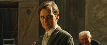 Movie still from “Manon of the Spring” (1986), directed by Claude Berri – A man in a suit and tie standing in front of a door; Close Up shot, Low angle