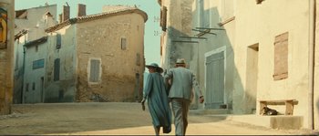Movie still from “Manon of the Spring” (1986), directed by Claude Berri – An older man and woman walking down a street; Wide shot, Low angle