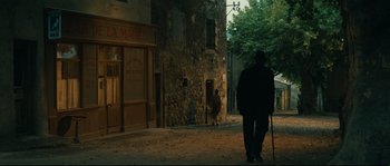 Movie still from “Manon of the Spring” (1986), directed by Claude Berri – A man walking down the street with a cane; Wide shot, High angle