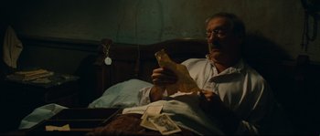 Movie still from “Manon of the Spring” (1986), directed by Claude Berri – An older man sitting in bed looking at a piece of paper; Close Up shot, High angle