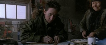 Movie still from “Map of the Human Heart” (1992), directed by Vincent Ward – A young man is writing on a piece of paper while sitting at a table; Close Up shot, High angle