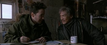 Movie still from “Map of the Human Heart” (1992), directed by Vincent Ward – Two men sitting at a table with a cup of coffee; Medium shot, Over the shoulder angle