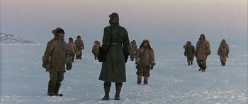 Movie still from “Map of the Human Heart” (1992), directed by Vincent Ward – A group of people walking across a snow covered field; Wide shot, Low angle