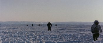 Movie still from “Map of the Human Heart” (1992), directed by Vincent Ward – A group of people walking across a snow covered field; Extreme Wide shot, High angle