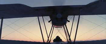 Movie still from “Map of the Human Heart” (1992), directed by Vincent Ward – A small plane is sitting on the ground at sunset; Wide shot, Low angle