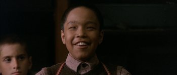 Movie still from “Map of the Human Heart” (1992), directed by Vincent Ward – A young boy wearing an apron smiling for the camera; Close Up shot, Low angle
