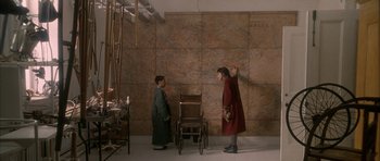 Movie still from “Map of the Human Heart” (1992), directed by Vincent Ward – Two people standing next to a wall with a map on it; Wide shot, High angle