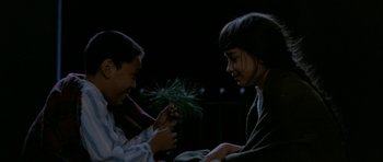 Movie still from “Map of the Human Heart” (1992), directed by Vincent Ward – Two young people are holding a plant in their hands; Medium shot, High angle