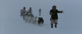 Movie still from “Map of the Human Heart” (1992), directed by Vincent Ward – A group of people walking in the snow with dogs; Wide shot, Low angle