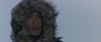 Movie still from “Map of the Human Heart” (1992), directed by Vincent Ward – A person wearing a coat and hat; Close Up shot, Low angle