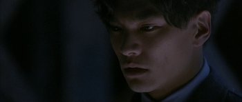 Movie still from “Map of the Human Heart” (1992), directed by Vincent Ward – A young man looking at the camera in the dark; Close Up shot, Low angle