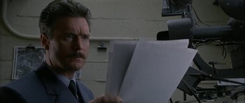 Movie still from “Map of the Human Heart” (1992), directed by Vincent Ward – A man in a suit and tie holding papers; Close Up shot, Low angle