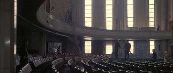 Movie still from “Map of the Human Heart” (1992), directed by Vincent Ward – A man is standing in an empty auditorium; Extreme Wide shot, Low angle