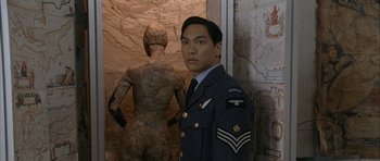 Movie still from “Map of the Human Heart” (1992), directed by Vincent Ward – A man in uniform standing in front of a map; Medium shot, High angle