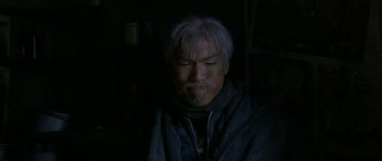 Movie still from “Map of the Human Heart” (1992), directed by Vincent Ward – An older man with grey hair and a gray jacket; Close Up shot, Low angle