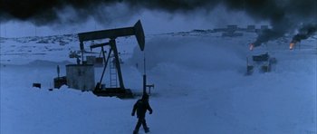Movie still from “Map of the Human Heart” (1992), directed by Vincent Ward – A person standing in the middle of a snow covered field near an oil well; Extreme Wide shot, High angle