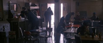 Movie still from “Map of the Human Heart” (1992), directed by Vincent Ward – A group of people standing in a room with tables; Wide shot, High angle
