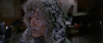 Movie still from “Map of the Human Heart” (1992), directed by Vincent Ward – A man in a fur coat and a hood covered in snow; Close Up shot, Over the shoulder angle