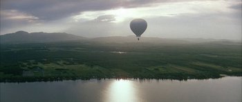 Movie still from “Map of the Human Heart” (1992), directed by Vincent Ward – A hot air balloon is flying over a large body of water; Extreme Wide shot, Low angle