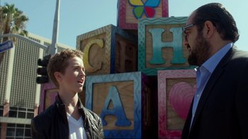 Movie still from “Maps to the Stars” (2014), directed by David Cronenberg – Two people standing in front of a building made of blocks; Close Up shot, Over the shoulder angle