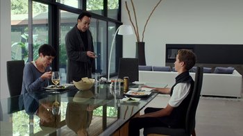 Movie still from “Maps to the Stars” (2014), directed by David Cronenberg – A man standing in front of a man sitting at a dining table; Medium shot, Over the shoulder angle