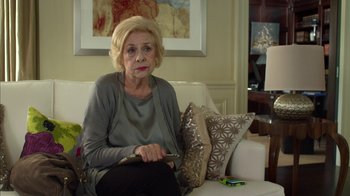 Movie still from “Maps to the Stars” (2014), directed by David Cronenberg – An older woman sitting on a couch holding a cell phone; Medium shot, Over the shoulder angle