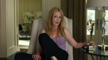 Movie still from “Maps to the Stars” (2014), directed by David Cronenberg – A woman sitting in a chair with her legs crossed; Medium shot, Over the shoulder angle