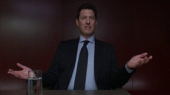 Movie still from “Maps to the Stars” (2014), directed by David Cronenberg – A man wearing a suit and tie sitting at a table; Medium shot, Low angle