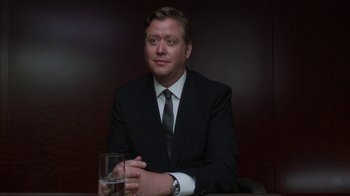 Movie still from “Maps to the Stars” (2014), directed by David Cronenberg – A man sitting at a table with a glass of water in front of him; Close Up shot, Low angle