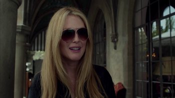 Movie still from “Maps to the Stars” (2014), directed by David Cronenberg – A woman with blond hair wearing sunglasses and smiling; Close Up shot, Over the shoulder angle