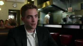 Movie still from “Maps to the Stars” (2014), directed by David Cronenberg – A person wearing a suit and tie; Close Up shot, Over the shoulder angle