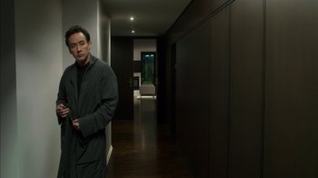 Movie still from “Maps to the Stars” (2014), directed by David Cronenberg – A man standing in a dark room in front of an open door; Medium shot, High angle