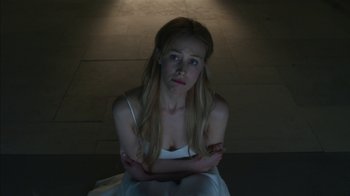 Movie still from “Maps to the Stars” (2014), directed by David Cronenberg – A woman sitting on the ground with her arms crossed; Medium shot, Low angle