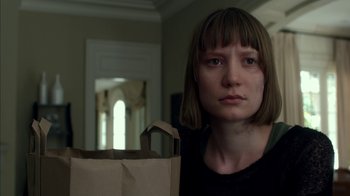 Movie still from “Maps to the Stars” (2014), directed by David Cronenberg – A woman holding a paper bag in a living room; Close Up shot, Over the shoulder angle