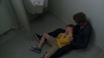 Movie still from “Maps to the Stars” (2014), directed by David Cronenberg – A man and a boy laying on the floor in front of a urinal; Medium shot, Overhead angle